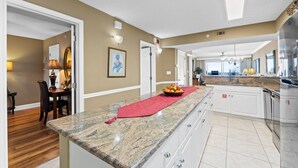 A spacious kitchen with a granite countertop, white cabinets, and a red placemat. - SL 502: Palm Bay Villa - Tropical Dreams with Gulf Coast Views! (Fort Walton Beach)