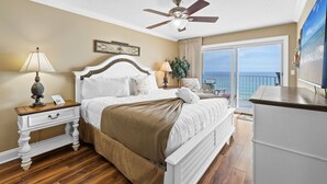 A bedroom with a bed, a nightstand, a ceiling fan, a window with a view, and a TV. - SL 502: Palm Bay Villa - Tropical Dreams with Gulf Coast Views! (Fort Walton Beach)