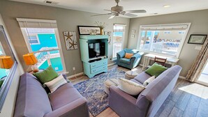 A living room with two sofas, a TV stand, and a ceiling fan. - Unwind in Style at Elysium (Surf City)