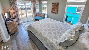 A bedroom with a bed, a TV, a desk, and a balcony. - Unwind in Style at Elysium (Surf City)