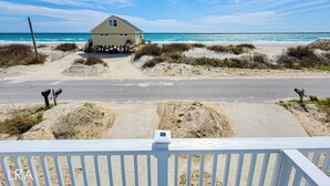 A beach house with a sandy driveway and a view of the ocean. - Unwind in Style at Elysium (Surf City)