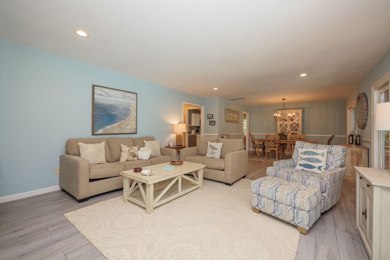 A living room with a beige sofa, a patterned armchair, and a coffee table.