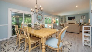 Un comedor con una mesa y sillas de madera, un candelabro y vistas al exterior a través de amplios ventanales.