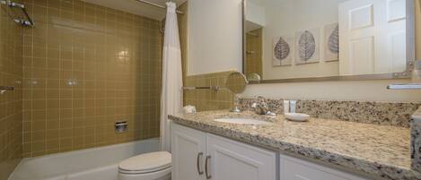 A bathroom with a bathtub, toilet, and a shower area.