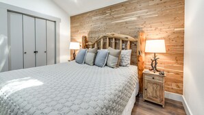 A bedroom with a wooden headboard, a bed with a patterned bedspread, two bedside tables with lamps, and a wardrobe. - 'Moondance' Ruidoso Retreat w/ Hot Tub & Views! (Ruidoso)