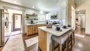 A modern kitchen with white cabinets, a central island, and wooden flooring. - 'Moondance' Ruidoso Retreat w/ Hot Tub & Views! (Ruidoso)