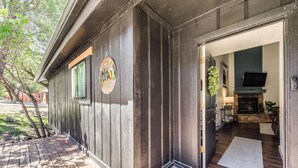 A wooden cabin with a welcome sign, a fireplace, and a TV in the living area. - 'Moondance' Ruidoso Retreat w/ Hot Tub & Views! (Ruidoso)