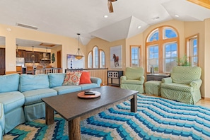 A spacious living room with a blue sofa, a wooden coffee table, and a patterned rug.