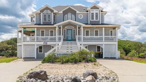 Et toetagers hus med en veranda, en blå dør og en lille have med sten og planter.