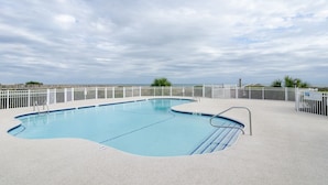 Piscina com cerca branca e vista clara do céu.