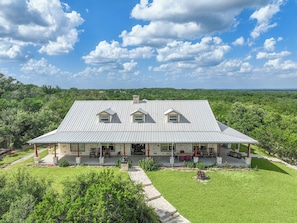 Une grande maison avec un toit en métal, une véranda et une pelouse bien entretenue.
