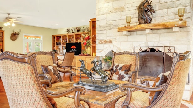 Un salon traditionnel avec une cheminée en pierre, un téléviseur et une statue de cheval décorative.
