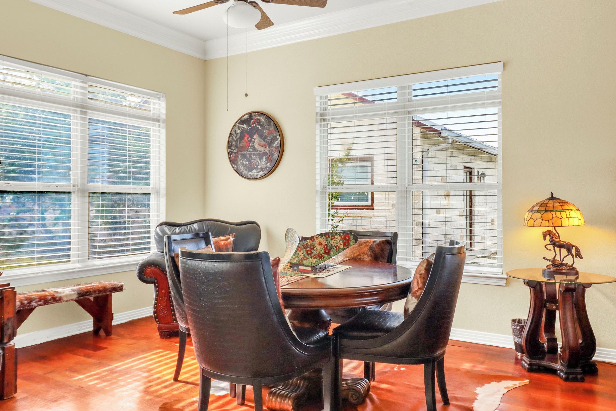 A dining area with a round table, leather chairs, a bench, and a lamp.