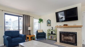 A living room with a fireplace, a television, a sofa, a coffee table, and a bookshelf. - Popular townhome in heart of Wrightsville Beach! (Wrightsville Beach)