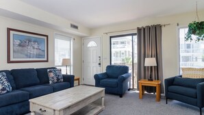 A living room with a sofa set, a coffee table, a blue armchair, and a lamp. - Popular townhome in heart of Wrightsville Beach! (Wrightsville Beach)