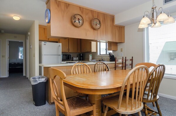 Une cuisine avec des meubles en bois, un îlot central et une table à manger avec des chaises.