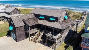 A coastal building with multiple levels, a staircase, and a view of the ocean.