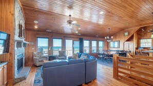 A wooden interior with a fireplace, seating area, and large windows.