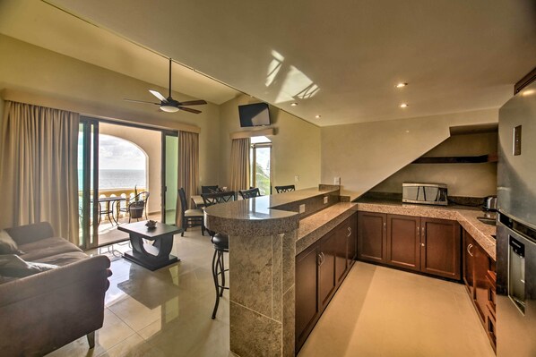 A modern kitchen with granite countertops, a built-in microwave, and a stainless steel refrigerator.