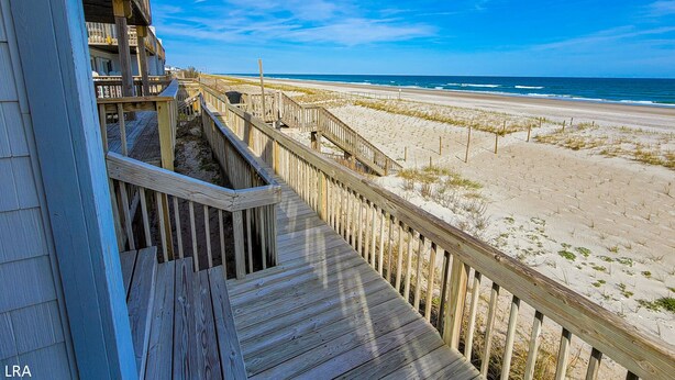 Un paseo marítimo de madera que conduce a una playa con vistas despejadas al océano.