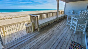 Una terraza de madera con vista a la playa y el océano.