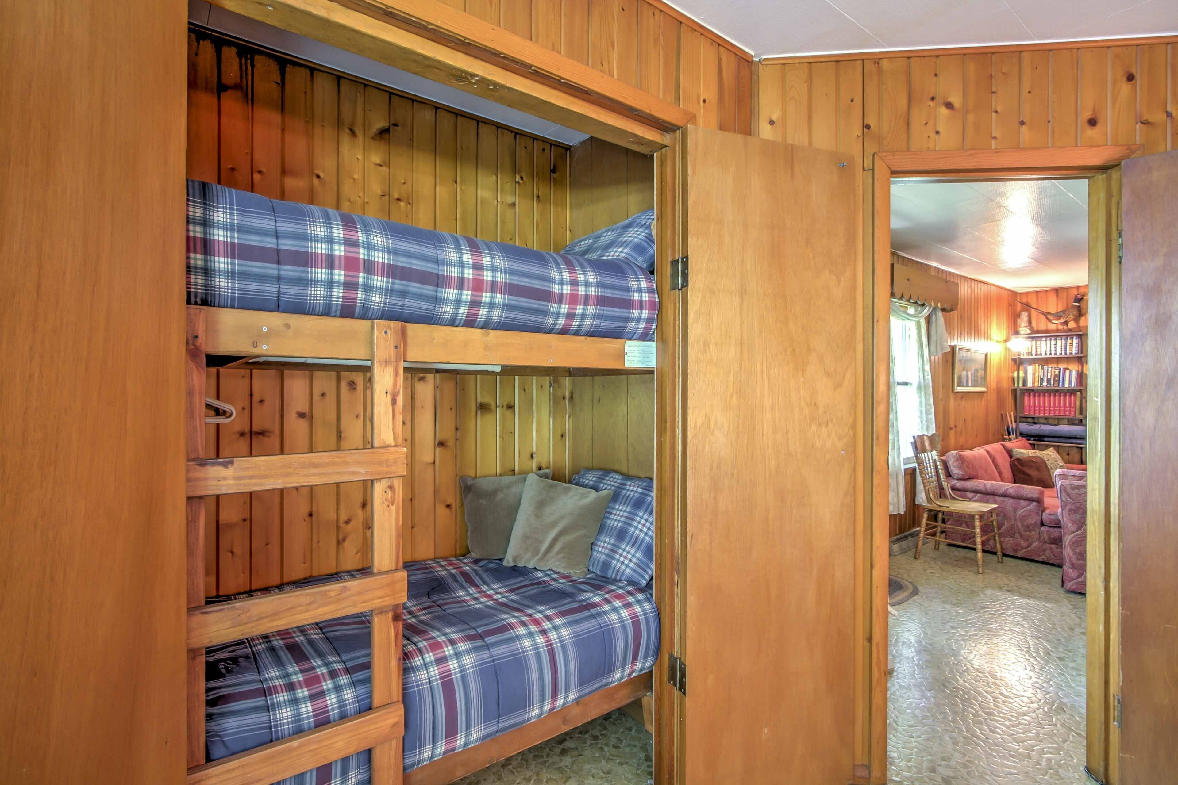 A wooden bunk bed room with plaid bedding and a small seating area.