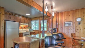 A kitchen with wooden cabinets, a refrigerator, a microwave, a sink, and a dining area with chairs and a table.