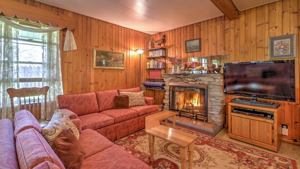 A cozy living room with a fireplace, a television, and a bookshelf.