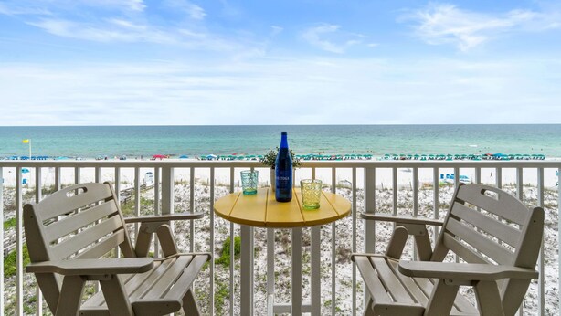 A beachside view with a table and two chairs, a bottle, and a glass on the table. - GD 406: Beachy Keen - Shell Yeah, It’s Beachfront! (Fort Walton Beach)