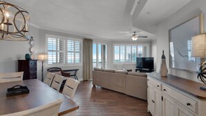 Uma sala de estar ampla com mesa de jantar, sofá e televisão.
