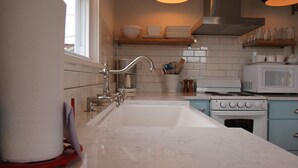 Een moderne keuken met een groot schiereiland, roestvrijstalen apparatuur en hanglampen.