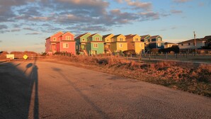 Een rij kleurrijke huizen langs een weg, met een heldere lucht.
