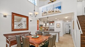 A spacious dining area with a wooden table and chairs, a large mirror, and a staircase leading to an upper level. - Luxury Poipu 4br Villa with AC Walk to the Beach! (224) (Koloa)