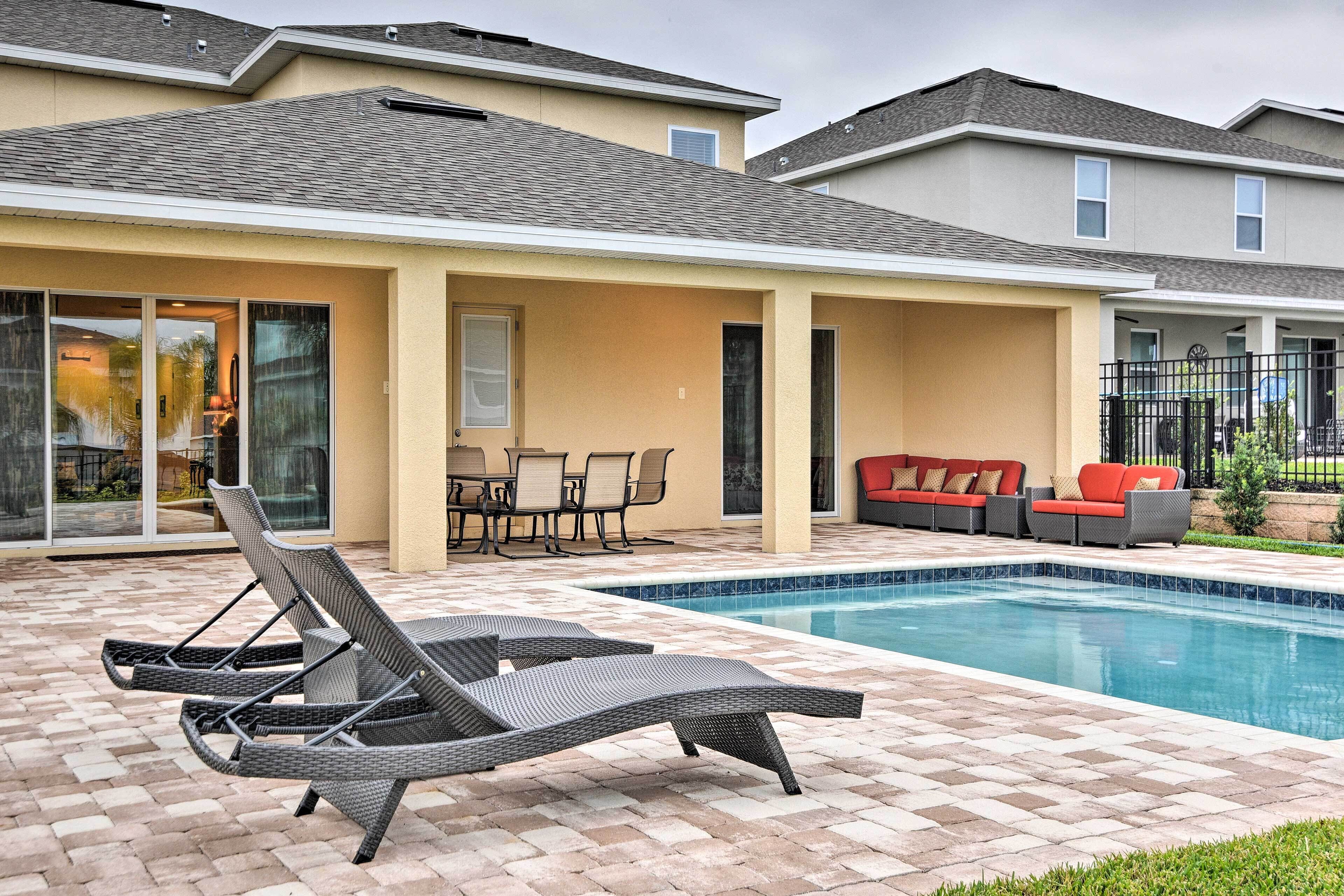Zona de piscina residencial con sillones de descanso, una mesa de comedor y un sofá.
