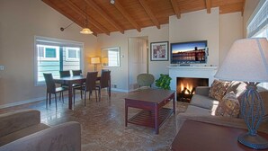 A living room with a fireplace, a television mounted above it, and a dining area with a table and chairs. - Wow, this fantastic upper unit just one house to the beach has peek-a-boo views (Newport Beach)