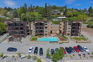 A multi-story hotel with a swimming pool, parking lot, and a view of a hillside with other buildings. - Marvelous Manson Condo, Steps to Lake Chelan Beach (Manson)