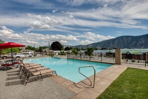 A swimming pool with lounge chairs and a red umbrella, surrounded by a fence and a mountain view. - Marvelous Manson Condo, Steps to Lake Chelan Beach (Manson)