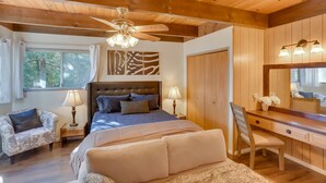 Un dormitorio con cama, escritorio, silla, ventilador de techo y ventana.