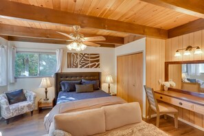 Un dormitorio con cama, escritorio, silla, ventilador de techo y ventana.