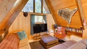 Un interior acogedor de madera, con un televisor grande, estanterías y una obra de arte original en la pared.