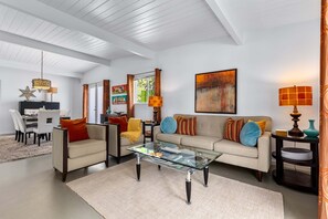 Ein modernes Wohnzimmer mit einem Glastisch, einer Couch und einem Essbereich mit Stühlen.