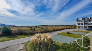 A coastal property with a paved driveway, grassy areas, and a building with multiple balconies. - Stay Coastal at Fenway at the Beach (North Topsail Beach)