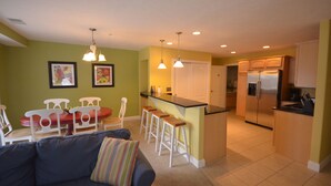 Una cocina compacta con una isla central, muebles blancos y un refrigerador.