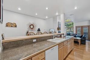 A modern kitchen with granite countertops, wooden cabinets, a built-in dishwasher, and a large window offering a view of the outdoors. - Ski-in/ski-out, Private Garage Parking! (Breckenridge)