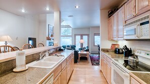 A modern kitchen with granite countertops, wooden cabinets, and stainless steel appliances.
