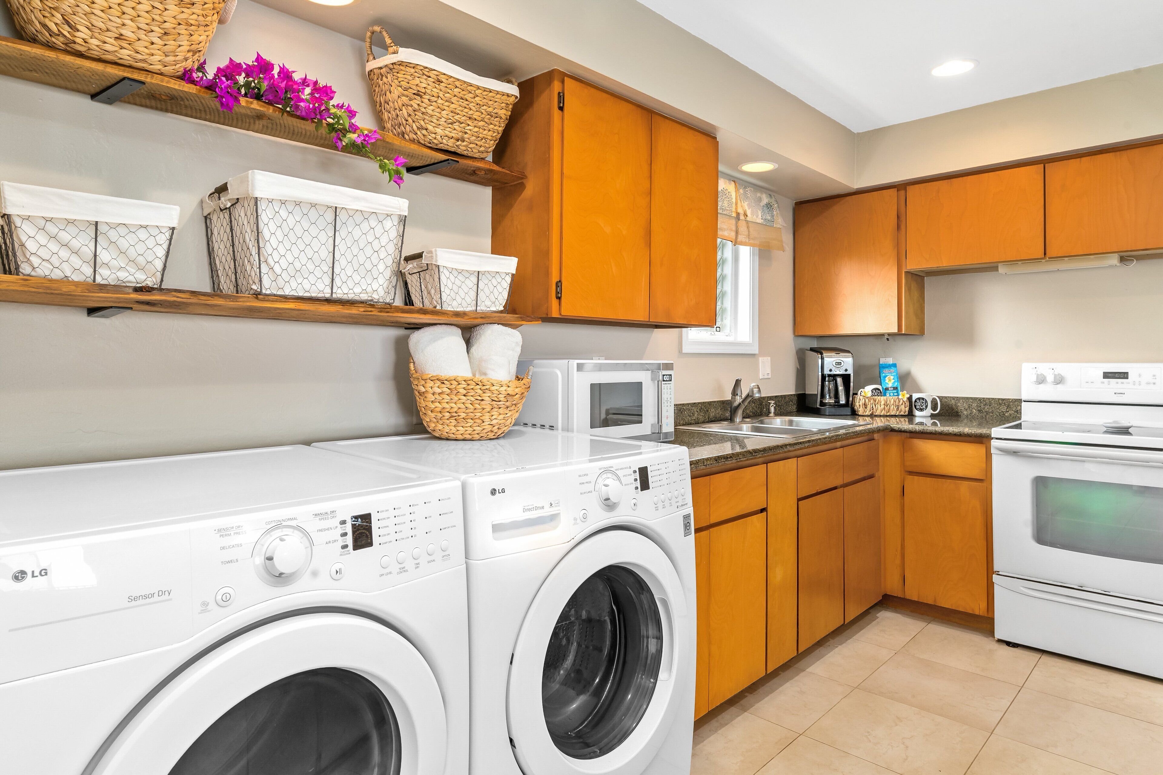 A modern kitchen with a washing machine, microwave, and oven.