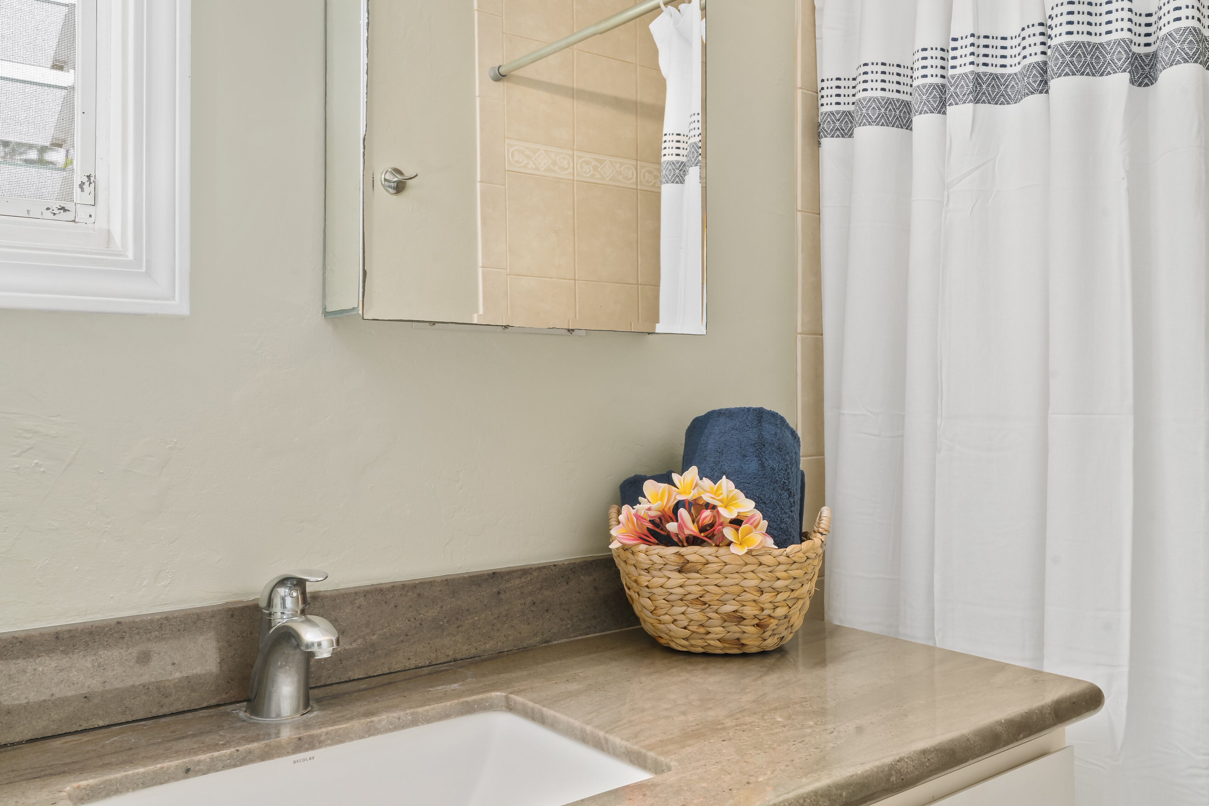 A bathroom with a sink, a mirror, a towel rack, and a decorative basket with flowers.
