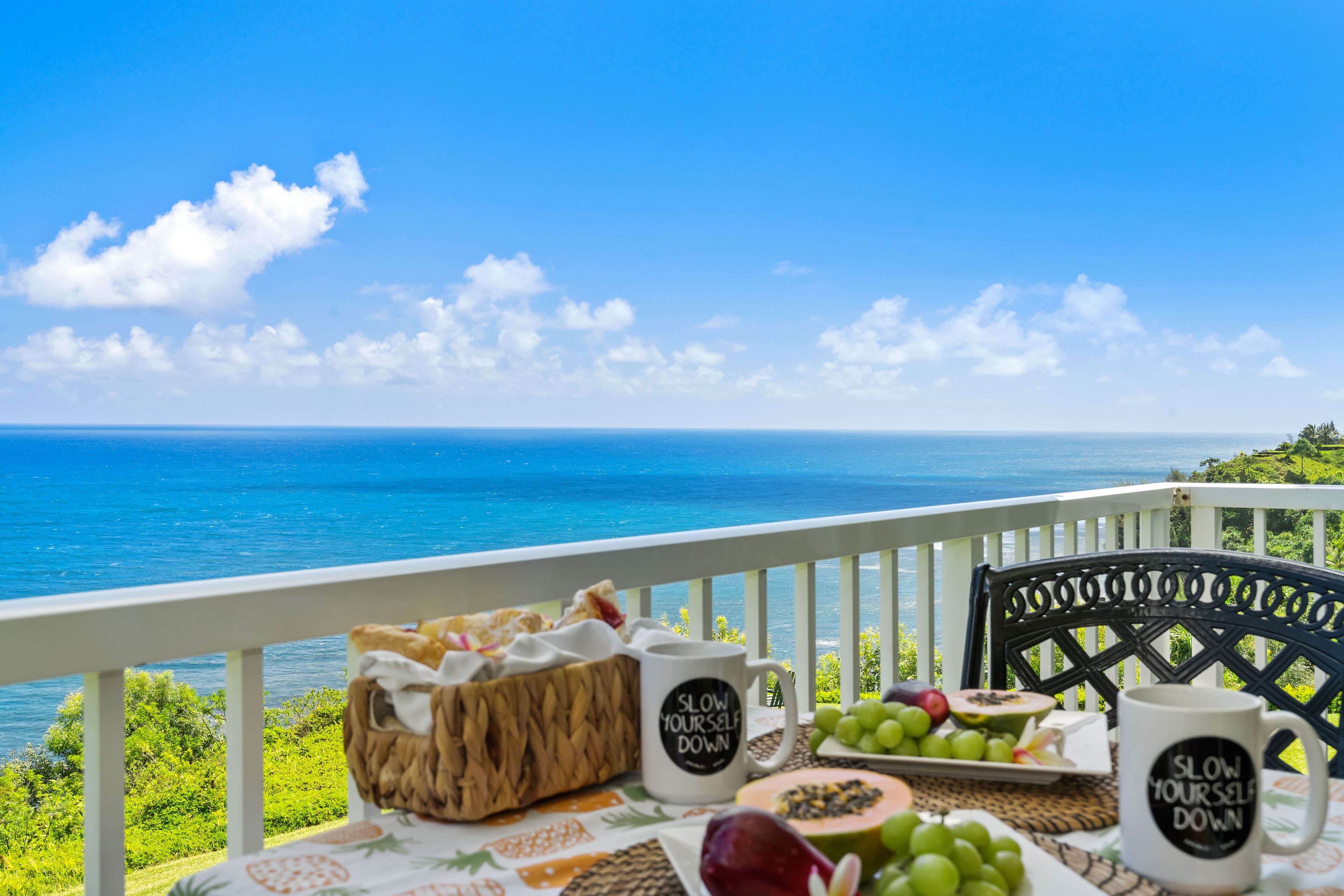 Une table dressée avec de la nourriture et des boissons sur un balcon donnant sur la mer.