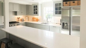 A modern kitchen with grey cabinets, a stainless steel refrigerator, and a white countertop. - School Street in the Old Village!! Charming, new construction with attention to detail! (Chatham)