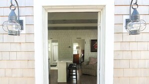 A doorway leading into a room with a brick wall, a wooden floor, a sofa, and two wall-mounted lanterns. - School Street in the Old Village!! Charming, new construction with attention to detail! (Chatham)